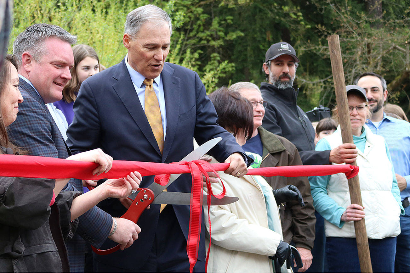 Bothell Mayor Andy Rheaume and Gov. Jay Inslee cut the ribbon to celebrate the city’s procurement of all of North Creek Forest, surrounded by local officials and others involved in the acquisition process. CATHERINE KRUMMEY / Bothell Reporter