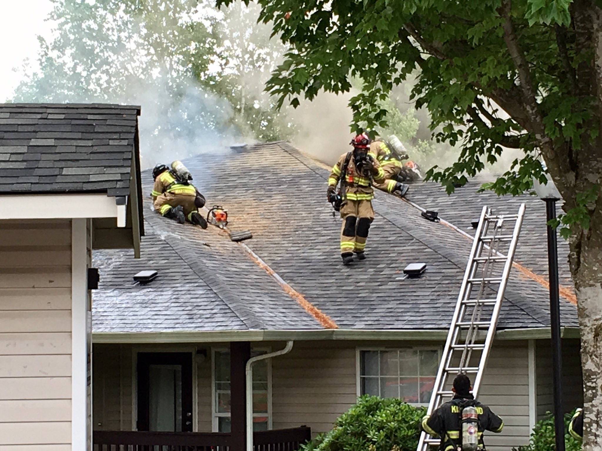 Bothell firefighters on the roof of an apartment building work to extinguish a fire that was mostly contained to the attic. Courtesy of Bothell Police Department