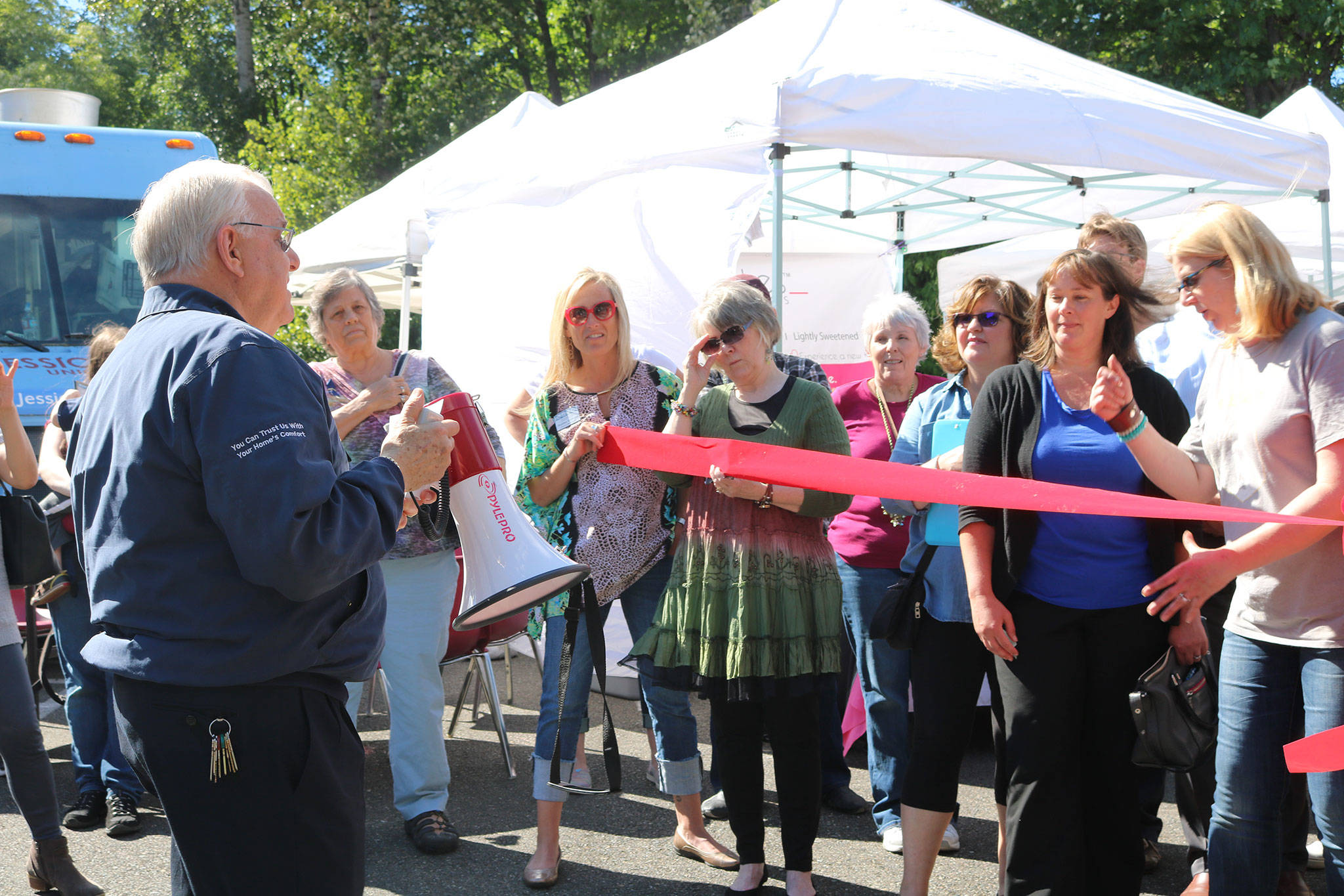 J.D. Davis (left), representing the Greater Bothell Chamber of Commerce, addresses the crowd at the Kenmore Community Market ribbon-cutting ceremony. CATHERINE KRUMMEY / Bothell-Kenmore Reporter