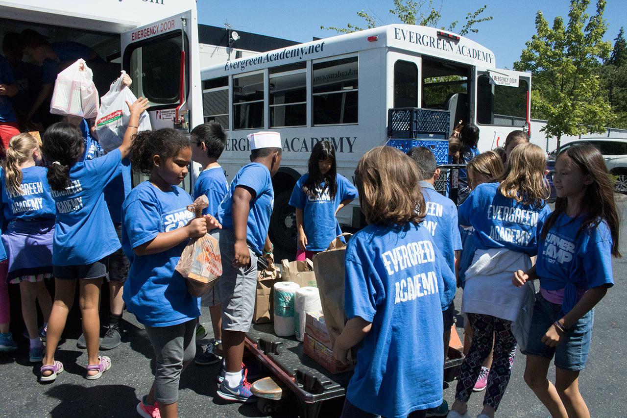 Students from Evergreen Academy Elementary School’s summer camp program pile the food and toiletry donations they collected onto a cart at Hopelink in Kirkland. Samantha Pak, Kirkland Reporter