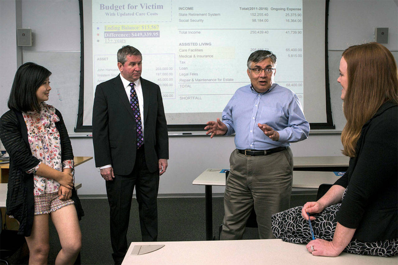 University of Washington Bothell’s forensic accounting class students Yiya You (left) and Rochelle McElroy (right) talk with professor Rajib Doogar (center right) and class mentor Kenneth Hines, a former IRS investigator. (Ian Terry / The Herald)