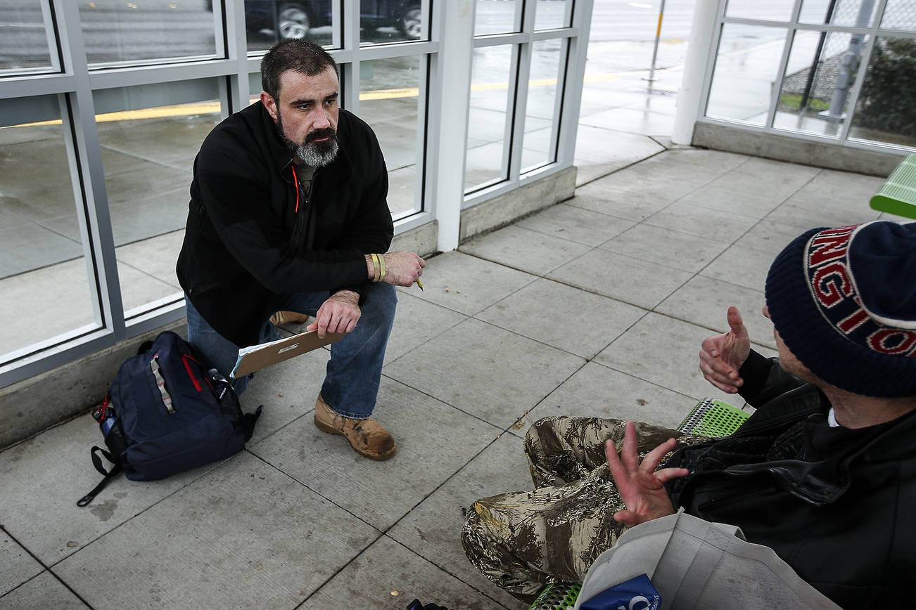 Volunteer Paul Olson (left), of Everett, completes a survey with a man at a bus stop on Smokey Point Boulevard on Tuesday, Jan. 23. Olson, a former U.S. Army infantryman, was homeless for two months following his time in the military. Ian Terry, The Herald