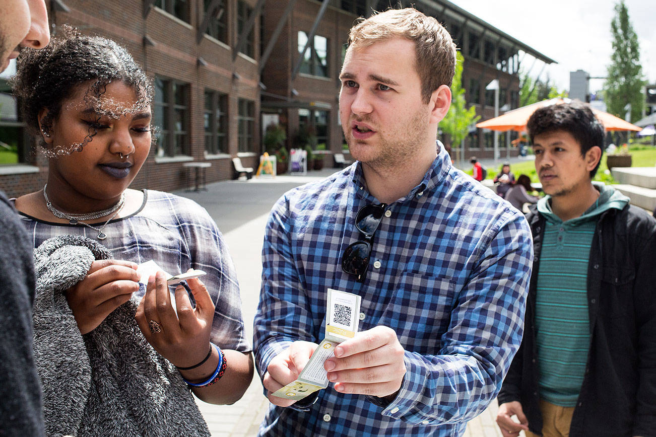 Cryptocurrency and Blockchain Club president Zach Nelson explains to a pair of students how the currency works while handing out free cryptocurrency at the University of Washington Bothell on Wednesday, May 9, 2018 in Everett, Wa. (Andy Bronson / The Herald)