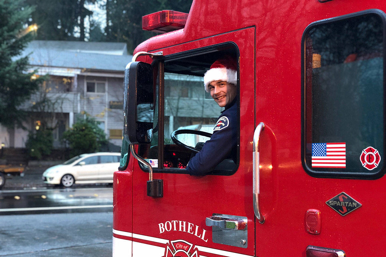 Firefighter Tyler Griffith sits in the driver’s seat wearing a Santa cap. Local firefighters will be decorating a fire engine this year as they drive around gathering donations and meeting with residents. Photo courtesy of the city of Bothell