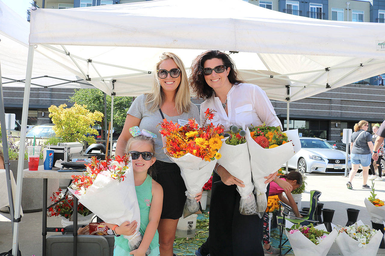 Danica Cardin (left) and her daughter Sydney and Tiffany Stetson buy flowers from an original market vendor on July 12. Stephanie Quiroz/staff photo