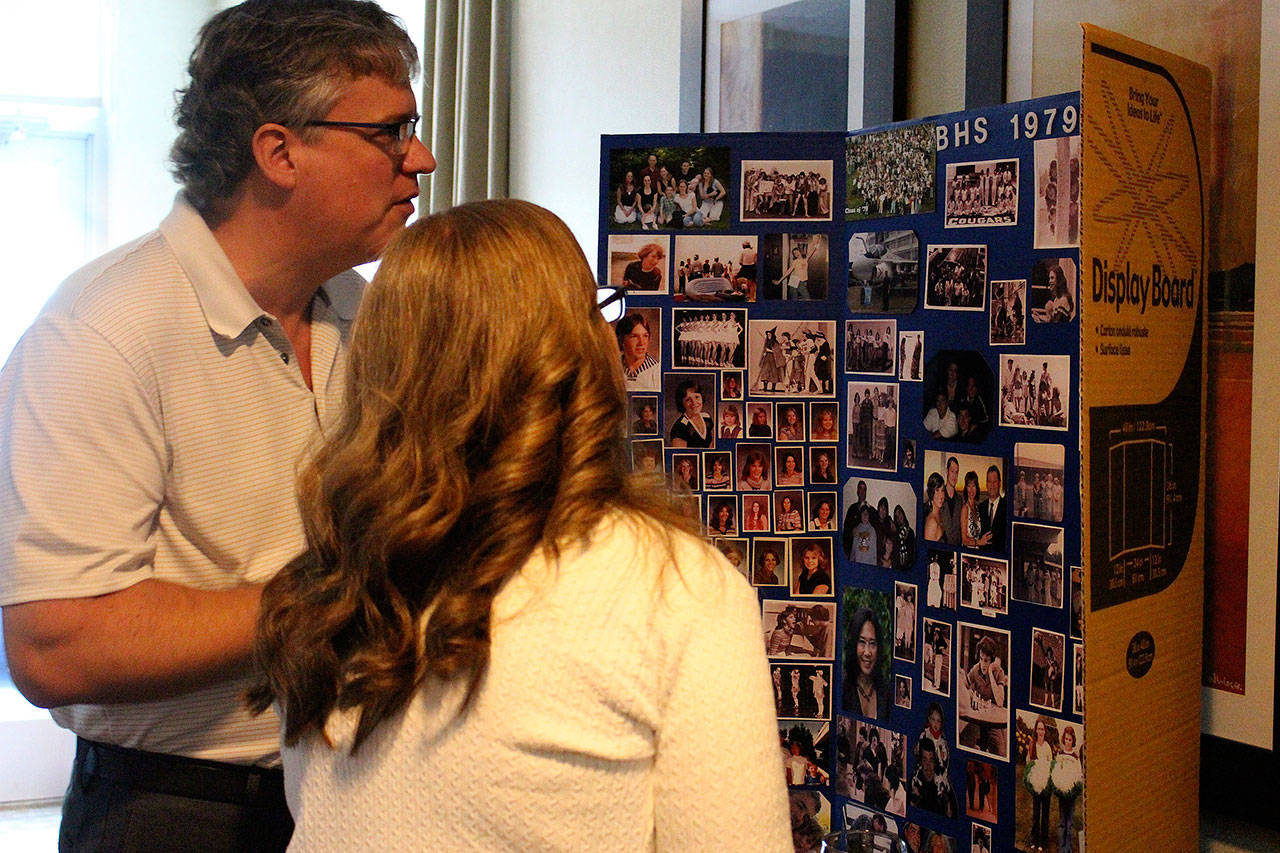 Photo by Madison Miller / staff photo                                Joe and Kathy Hanrahan look at old photos of classmates at the Bothell High School 40-year reunion. Joe, class of ‘79, and Kathy, class of ‘82, met in high school.