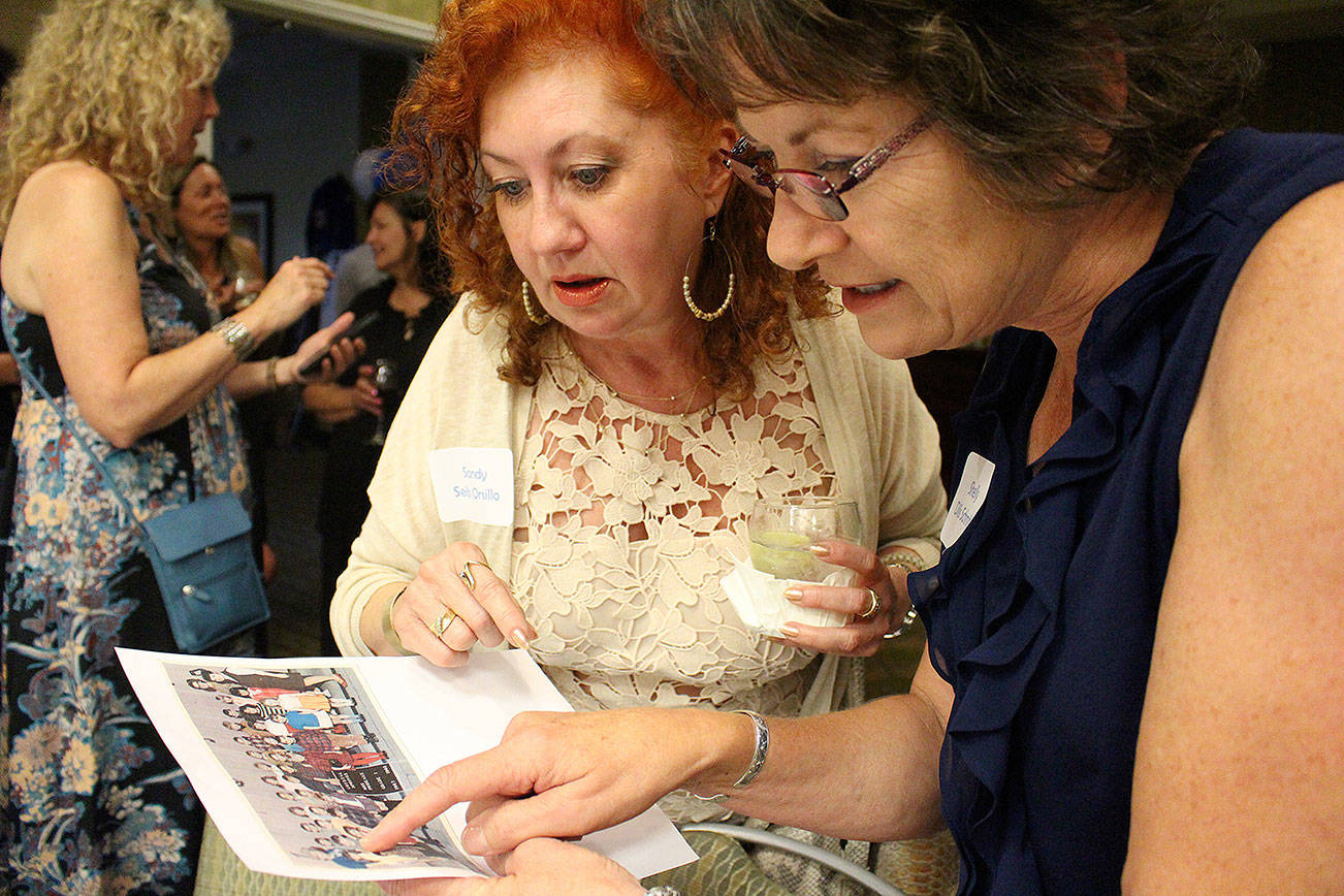 Madison Miller / staff photo                                Bothell High School class of 1979 reunite for 40-year reunion. Sandy Seib Orsillo and Shelly Schmidt look at old photos of classmates.