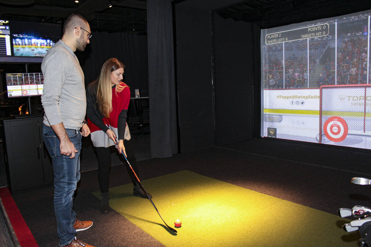 Bellevue residents Marko and Karla Ilicic play a hockey game in the Topgolf Swing Suite inside Forum Social House. Natalie DeFord/staff photo