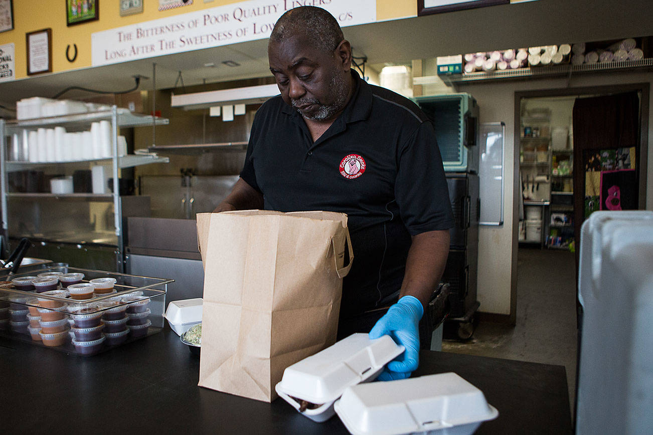 Carolina Smoke owner David Hayward packages up orders to go on March 22 in Bothell. Olivia Vanni/staff photo