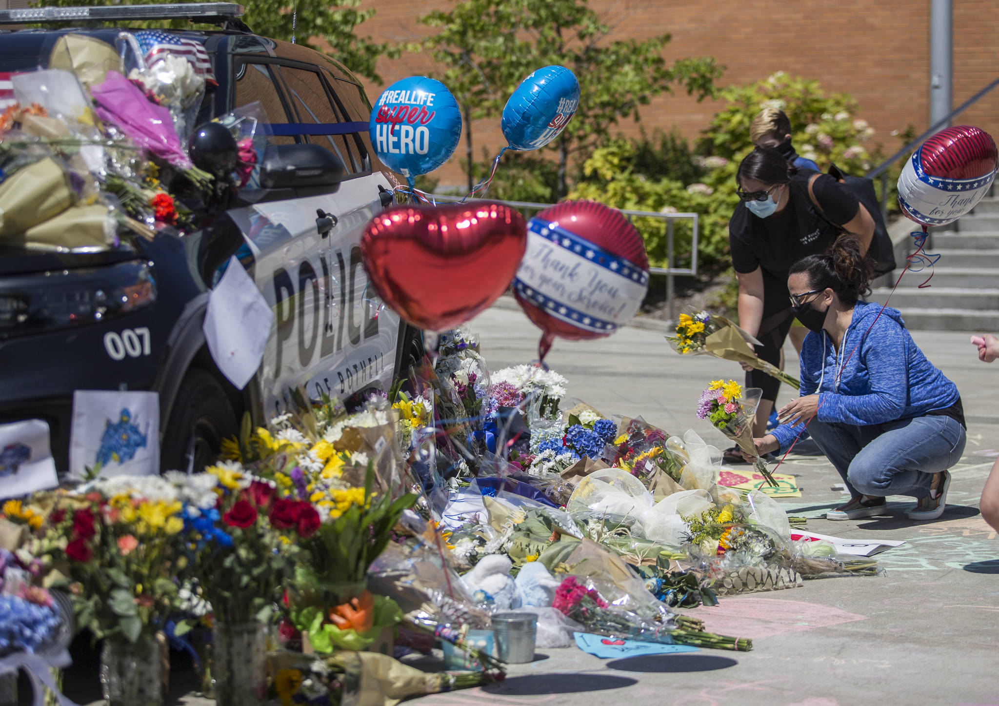 People place flowers at a memorial Tuesday in front of Bothell City Hall for a Bothell police officer who was killed Monday night. (Olivia Vanni / The Herald)