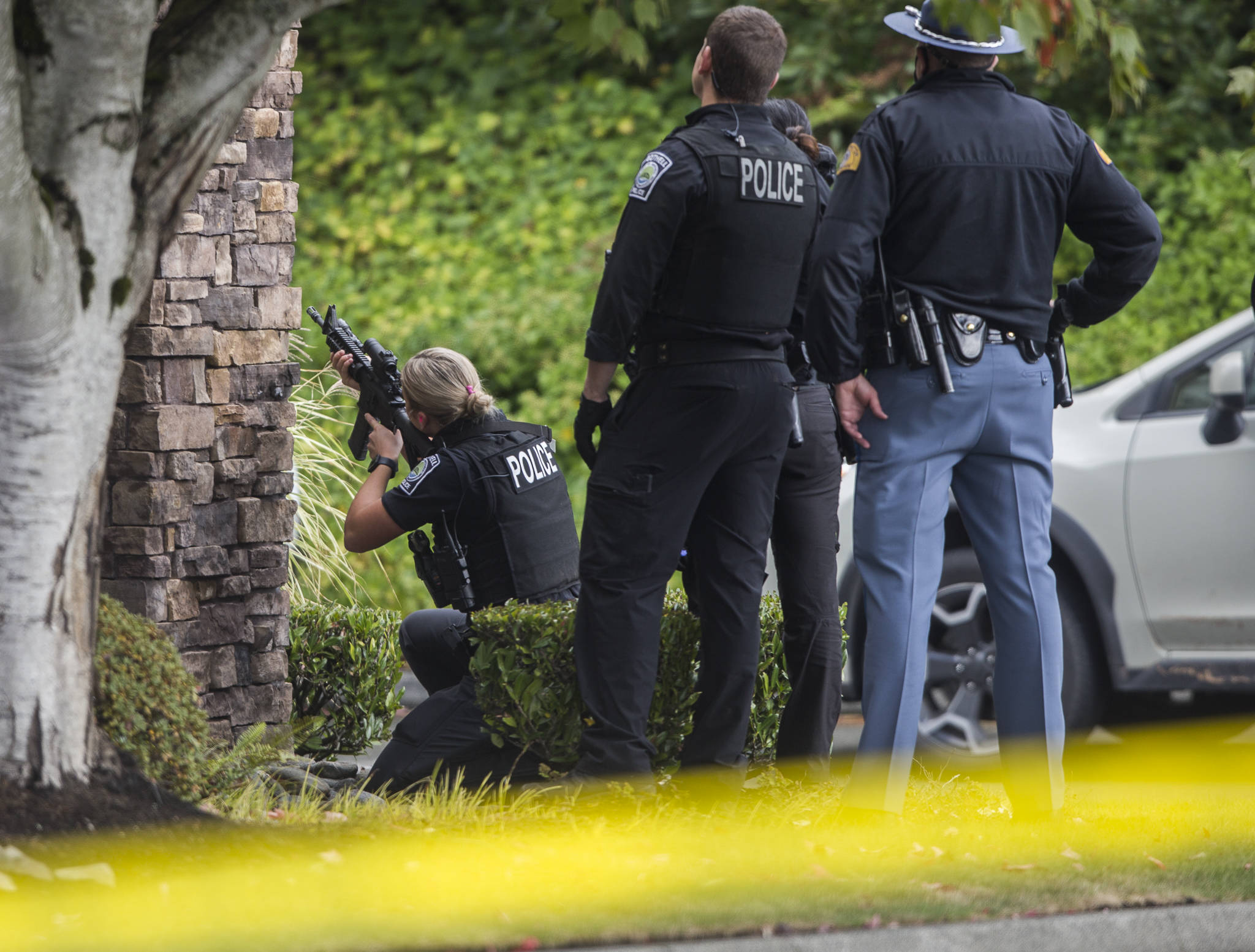 A police officer looks through a scope at a carjacking suspect on Wednesday near Mill Creek. (Olivia Vanni / The Herald)