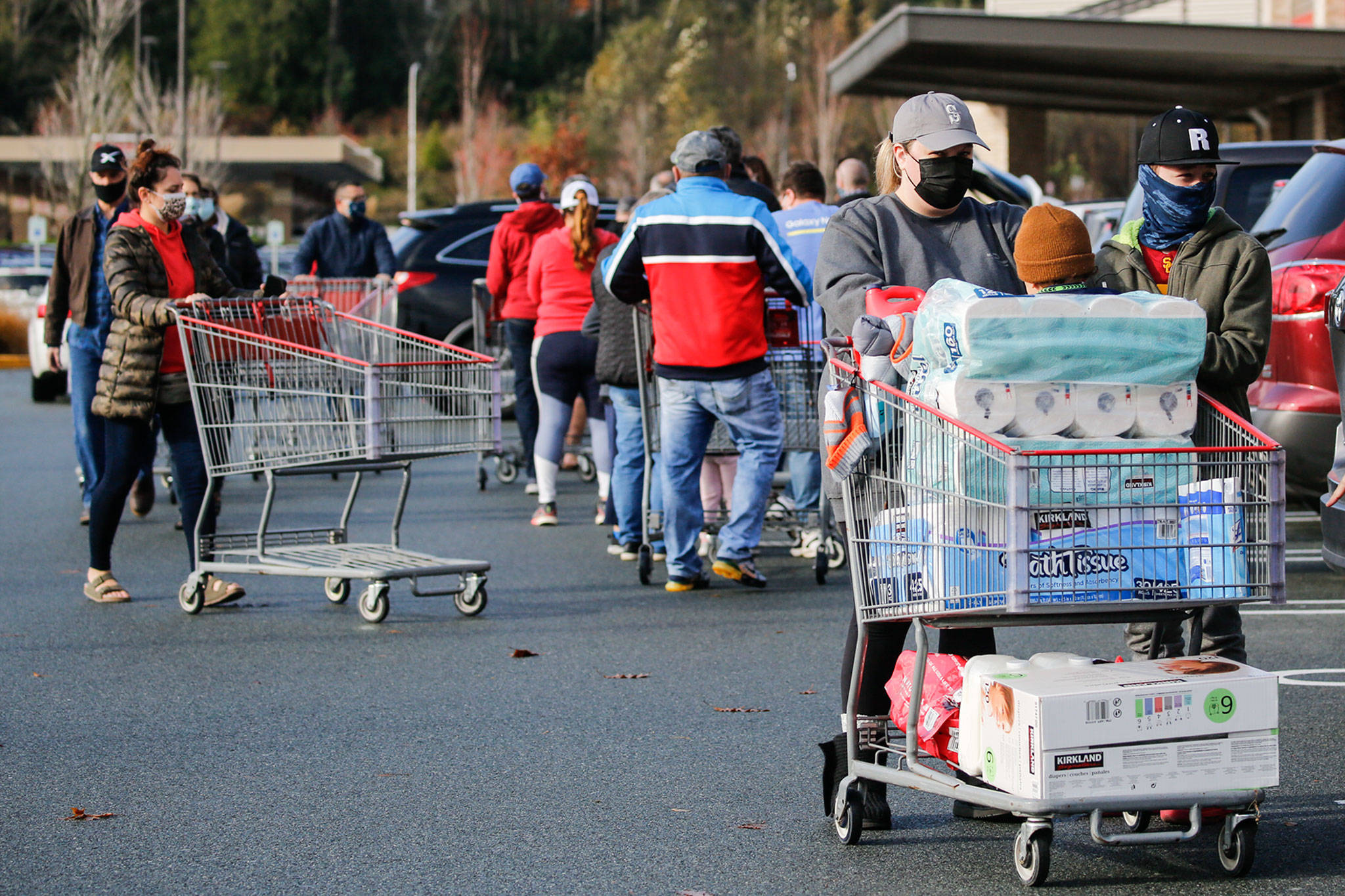 Costso customers unload groceries as the line to get in grows Sunday morning in Lynnwood. (Kevin Clark / The Herald)