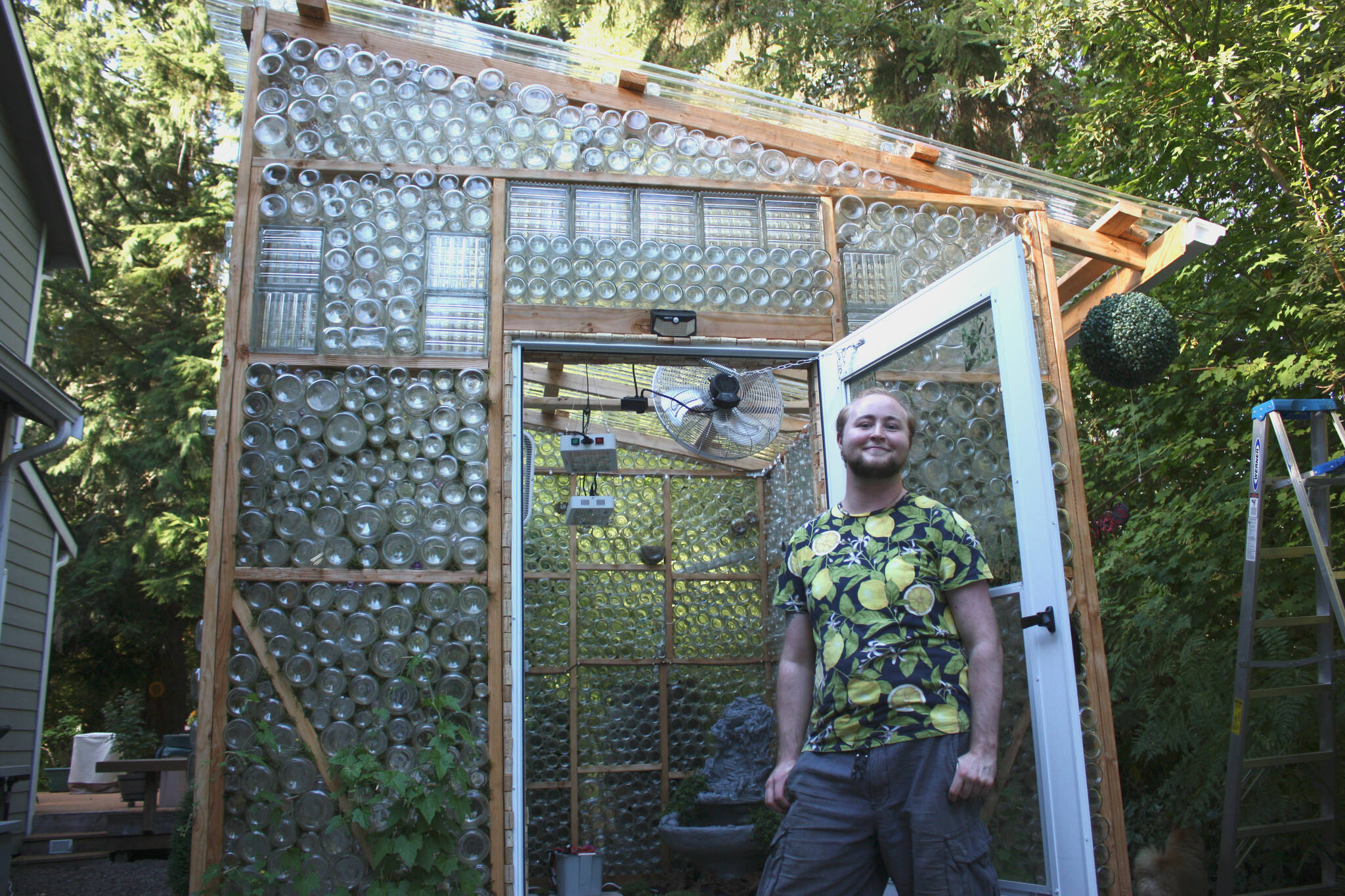 Axton Burton stands proudly in front of the greenhouse he made in his parent’s yard in Duvall, Wash. (photo by Cameron Sheppard)
