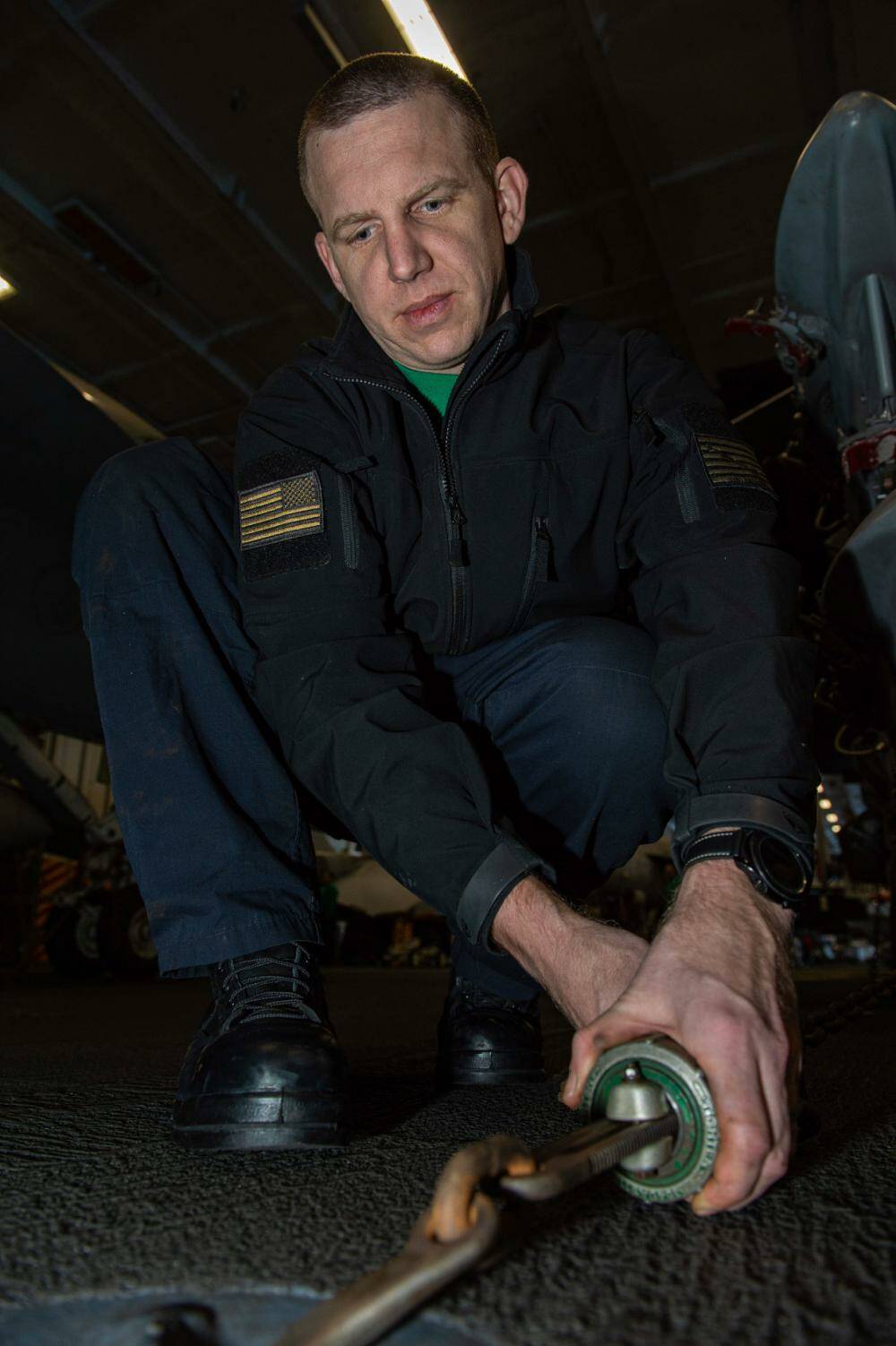 Aviation Structural Mechanic 1st Class Paul Moiter chains down a BRU-32 bomb rack in the hangar bay of the USS Harry S. Truman. Courtesy of U.S. Navy.