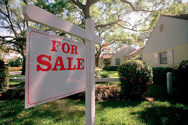 For sale sign hanging in front of house