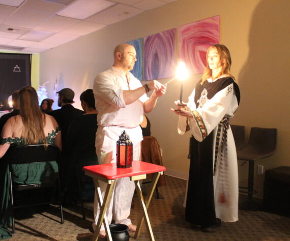 High Priest Kalu and High Preistess Syleena “Call The Corners,” a small ritual where a candle is lit at each direction of the Earth as the elements of each direction is called upon. Here they call on the guardian of the watchtower of the South, represented by red which symbolizes fire. Photo by Bailey Jo Josie/Sound Publishing.