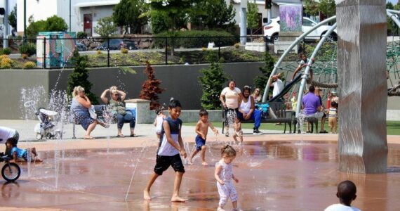 Families splash and play in the water at at Federal Way’s Town Square Park to cool off from a previous heatwave in the region. (File photo)