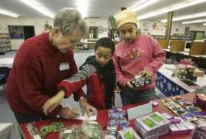Volunteer Mary Lanphear helps Rebecca and William Nsubuga Christmas shop for their family at Canyon Creek Elementary Dec. 16. Rebecca and William were shopping for their uncle