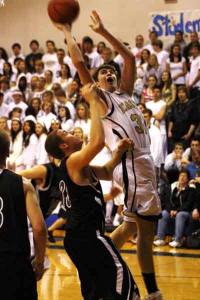 Cedar Park Christian forward Evan Scholten lays up a shot over the reach of Bellevue Christian forward Bryce Oldham during Friday's 1A Emerald City League archrival matchup at Cedar Park. Bellevue Christian won