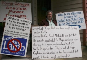 Bothell resident James Barnhart sits with his signs