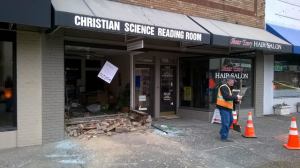 A worker clears broken glass and debris from the sidewalk outside the Bothell Christian Science Reading Room after a large silver truck drove through the storefront around 8:20 a.m. today.