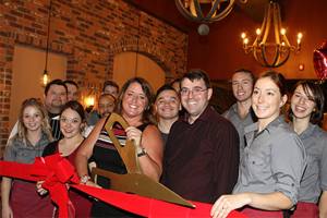 Owner Dusty DuBois (center, with the scissors) celebrates the grand opening of Revolve True Food and Wine Bar alongside the restaurant&rsquo;s staff. Contributed photo