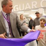 North Creek High School Principal Eric McDowell cuts a piece of ribbon for a young visitor during the open house on Nov. 21. The ribbon went quickly, as scores of onlookers crowded around for a slice. JOHN WILLIAM HOWARD/Bothell-Kenmore Reporter