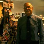 Dr. Robert J. Bendzak poses alongside a wall filled with pictures of his patients and their families. CATHERINE KRUMMEY / Kenmore Reporter