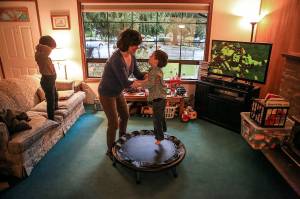Ian Fisher watches a game as his mother, Deanna Fisher, plays with her youngest autistic son, Colin Fisher, 4, at their home in Bothell. The Fishers are volunteering baby teeth for a national study to determine if prenatal exposure to chemicals increases a child&rsquo;s chances of developing the autism. (Kevin Clark / The Herald)