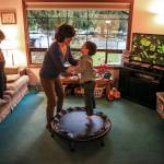 Ian Fisher watches a game as his mother, Deanna Fisher, plays with her youngest autistic son, Colin Fisher, 4, at their home in Bothell. The The Fishers are volunteering baby teeth for a study to determine if prenatal exposure to chemicals increases a child&rsquo;s chances of developing the autism. (Kevin Clark / The Herald)