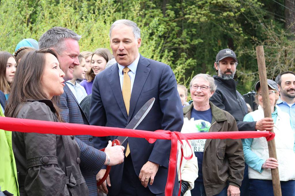 Bothell Deputy Mayor Davina Duerr, Bothell Mayor Andy Rheaume and Gov. Jay Inslee prepare to cut the ribbon to celebrate the city&rsquo;s procurement of all of North Creek Forest, surrounded by local officials and others involved in the acquisition process. CATHERINE KRUMMEY / Bothell Reporter