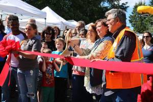 Kenmore Community Market manager Jenni Jensen (with the scissors) cuts the ribbon to celebrate the market&rsquo;s opening. CATHERINE KRUMMEY, Bothell-Kenmore Reporter