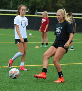 Kelsy Berge, right, kicks the ball while teammate Rachel Conchi watches during last Friday&rsquo;s practice at Inglemoor High. Andy Nystrom, Bothell-Kenmore Reporter