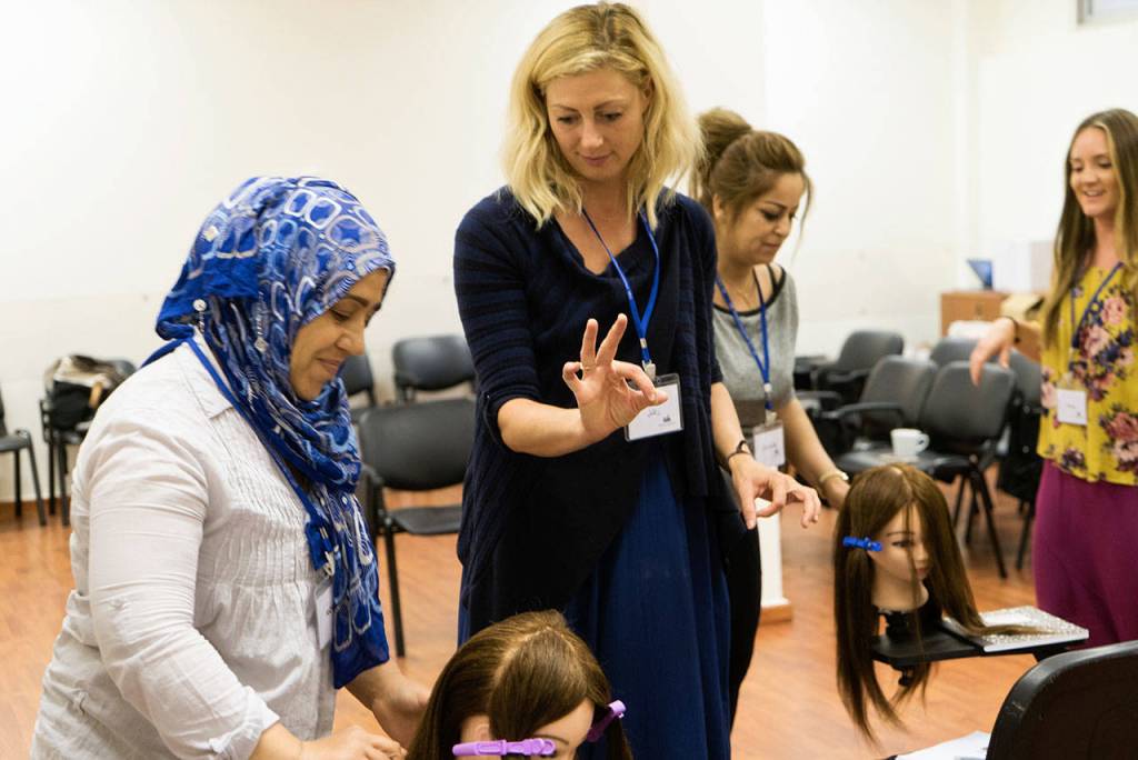Rachel Hile of The Beyond Project oversees a student in Lebanon learning how to cut and style hair. Courtesy of Rachel Hile
