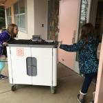 Two students at Moorlands Elementary School in Kenmore wheel a reserved computer cart into their building. Courtesy of Northshore School District