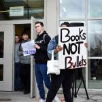 Bellevue High School student Charlie Kern holds a sign calling for more guns, less crime as another student holds a sign that reads books, not bullets. The walkout was student-led and students were able share their opinions and have a dialogue with one another. Raechel Dawson/staff photo