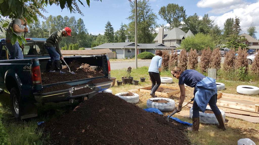 Denise Tarter and her neighbors, Martin Krienke, Frank Mateo and Margaret Mateo, offload fertilized soil for the 13th Place Garden. Photo courtesy of Denise Tarter