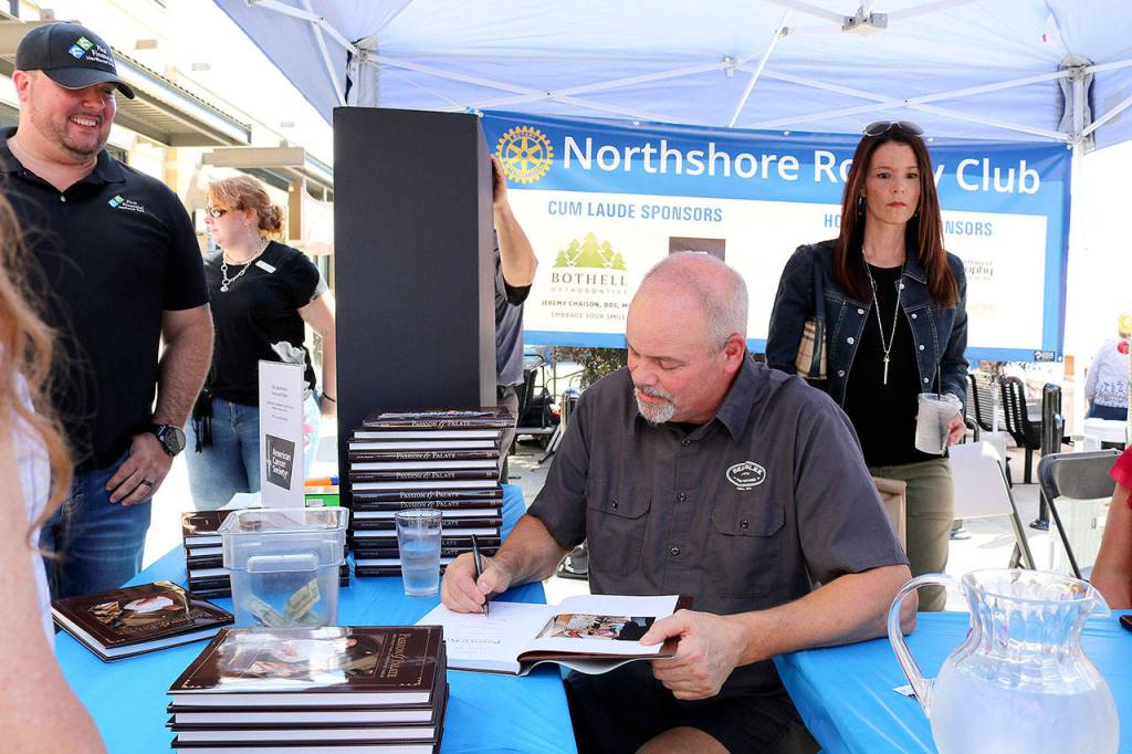 John Howie, owner and chef for Beardslee Public House signs a copy of his cook book for a customer on July 12. Stephanie Quiroz/staff photo