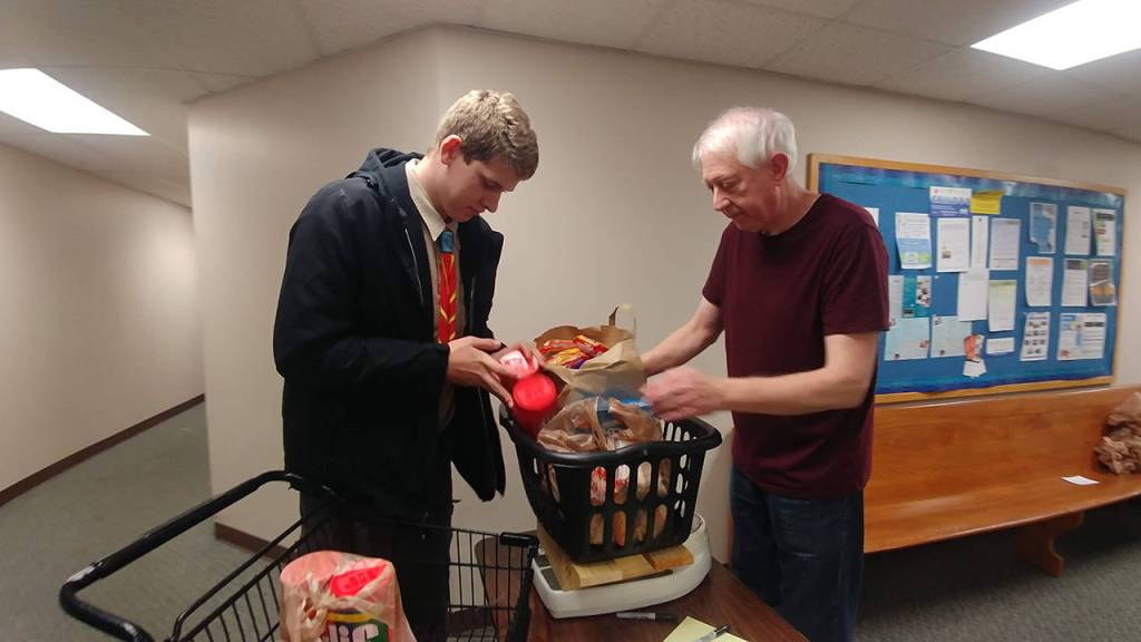 Photo courtesy of of Boy Scouts Troop 622                                 Scout Ryan Waldrop (left) hands off food at the Woodinville Storehouse Food Bank.