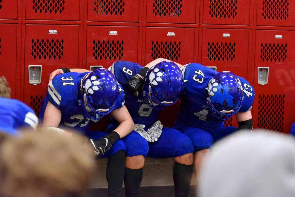 Ryan Metz (31), Tala Tevaga (9) and Colin Fisherkeller (43) embrace in the locker room following the state championship game. Photo courtesy of Greg Nelson