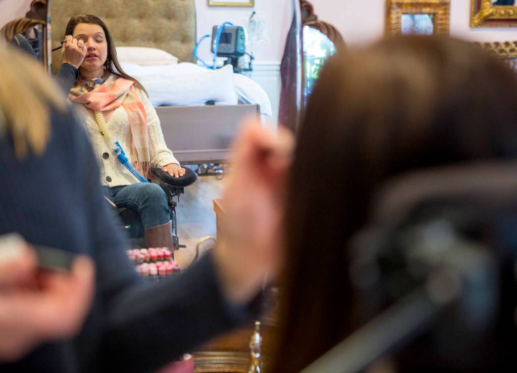 Lindsey Holland, a nurse, puts eye shadow on Loa Griesbach. (Olivia Vanni / Everett Herald)