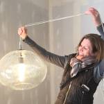 Artist Julie Conway of Illuminata Glass holds one of her light fixture creations in Hashtag Cannabis Seattle storefront, currently being remodeled. Some of her works will be a part of the new Redmond store as well, part of the companys support of local artists and businesses, especially those operated by women. Photo by Kim Bevington