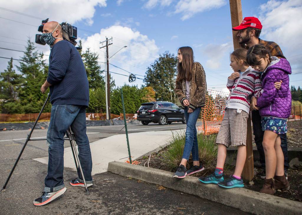 Television crews and onlookers watch as a carjacking suspect makes his way down a ladder on Wednesday near Mill Creek. (Olivia Vanni / The Herald)